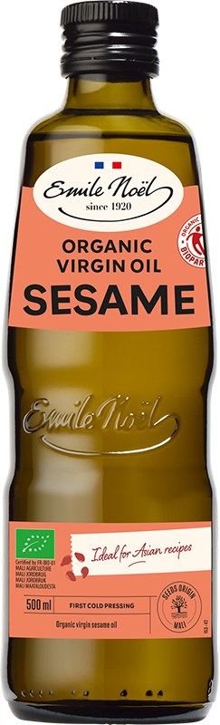 A 500ml bottle of Emile Noël organic virgin sesame oil with a green cap, brown glass, and a beige and orange label showing fair trade and organic certifications. Cylindrical bottle; cap is smooth, plastic. Label uses serif fonts for brand name and sans-serif for other information. Key certifications are in icon form near the label bottom. Plain white background with no props or people. Studio product shot at eye level.