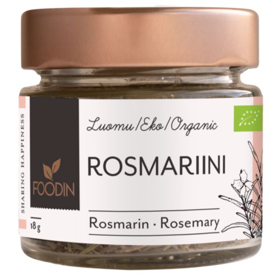 A glass jar of Foodin organic rosemary with a rose-gold metal lid, cylindrical shape, and clear body showing dried rosemary leaves. The surface of the jar is glossy. The label is matte, dark with white sans-serif text in Finnish, German, and English stating product name and weight (18g), plus simple green botanical illustrations. Studio-style white background. No people or hands present.