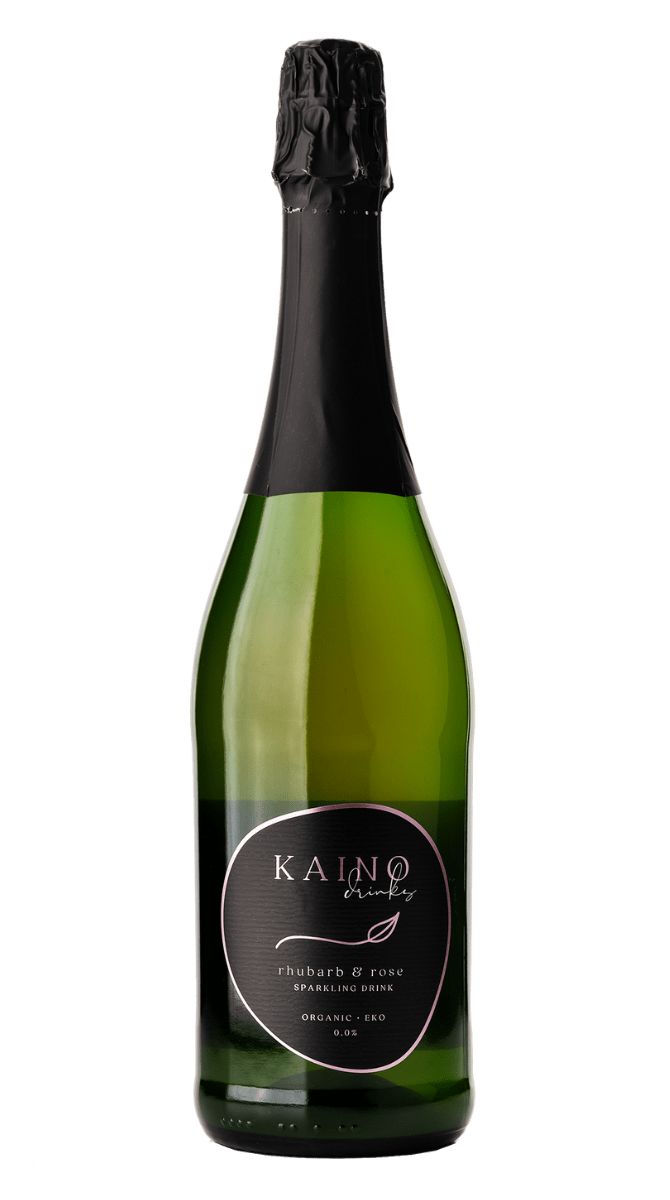 A green glass bottle of Kaino rhubarb & rose sparkling drink features a black foil-wrapped top and an elegant black label, showcasing its refined botanical blend. The bottle has a smooth, glossy surface and a tall, narrow neck. White and gold serif text appears on the black label. Background is plain white with minimal shadows. No people or hands are visible in the image.