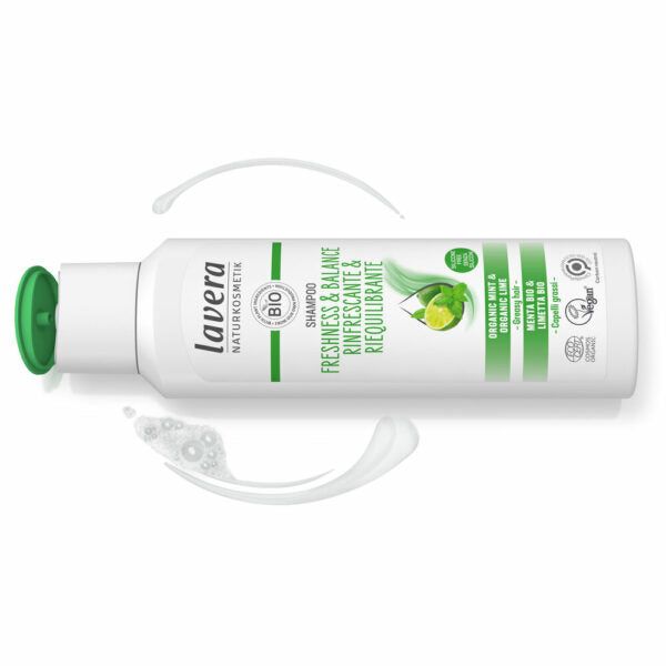 White bottle of Lavera shampoo with a green flip cap, labeled Freshness & Balance, featuring organic lime and mint, shown alongside some refreshing minty shampoo product swirls. The bottle is plastic with a smooth surface, upright cylinder shape. Label uses sans-serif typography in varying weights. Product is set against a plain background; no people or props are present in the image.