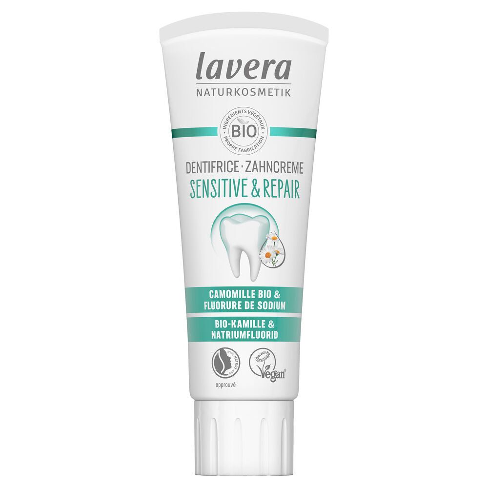 A white tube of Lavera Sensitive & Repair toothpaste with chamomile, labeled vegan and organic, featuring a tooth image and green-blue herbal accents. The packaging is plastic, has a matte surface, cylindrical shape with a flat cap. Text on the front includes product name and key features in sans-serif fonts. The background is plain white; no people or actions are present.