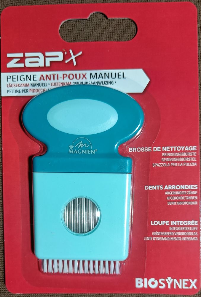 A packaged manual lice comb called ZapX by Magnien, featuring rounded teeth and a built-in magnifying glass for precise removal. The comb is visible through a clear plastic window in the packaging. The packaging is rectangular and red with a matte finish, includes multilingual text in white, yellow, and black fonts, and displays the Biosynex logo at the bottom. Plain white background, product shot only.
