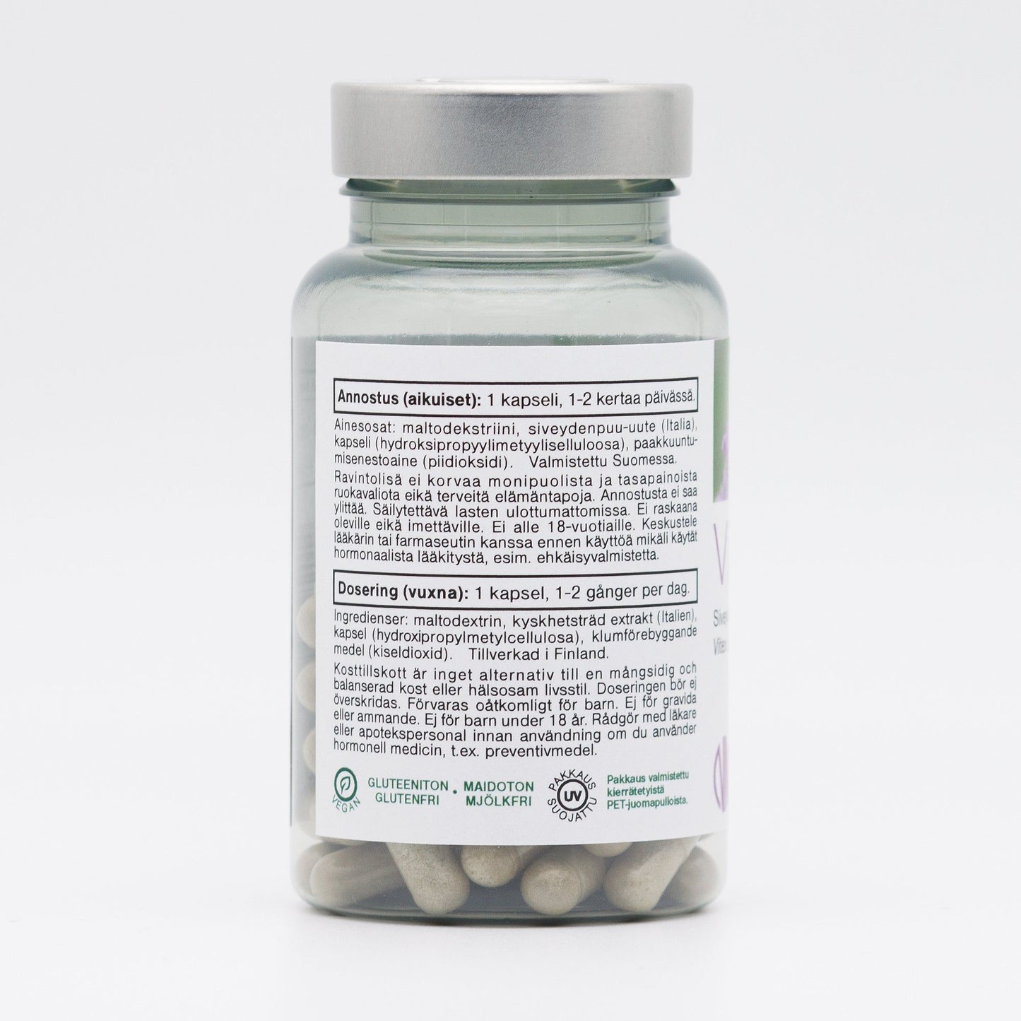 A transparent bottle with a silver lid contains white capsules. The surface of the bottle is smooth and glossy. The label has clear, sans-serif typography and includes dosage instructions in Finnish and Swedish, plus icons for gluten-free, dairy-free, and soy-free. No people or hands are present. Background is plain white; image is a centered product shot.