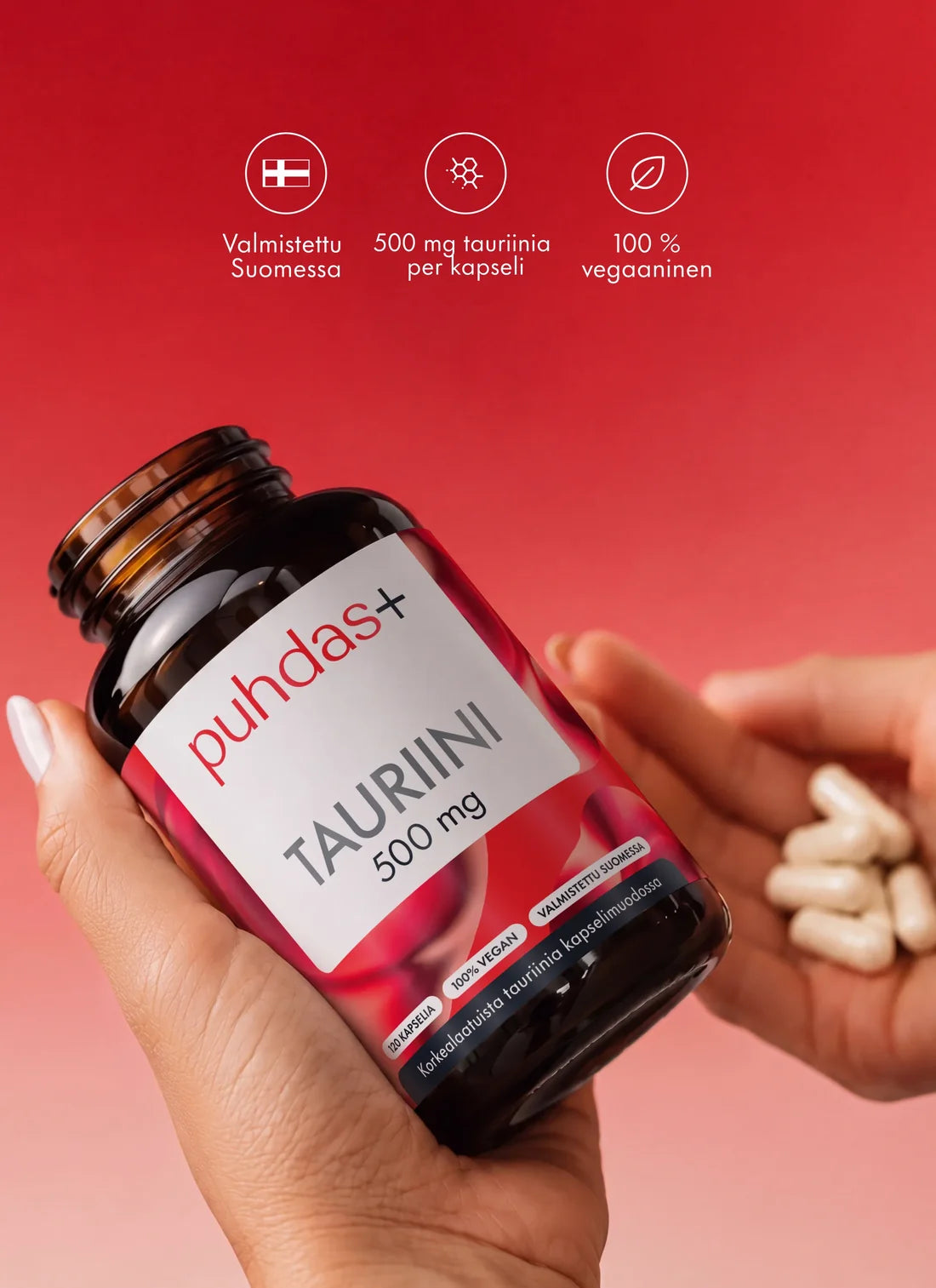 Käsi pitelee Puhdas+ Tauriini -pulloa punaisella taustalla, toisessa kädessä kapseleita, yllä ikonit valmistusmaasta, annoksesta ja vegaanisuudesta