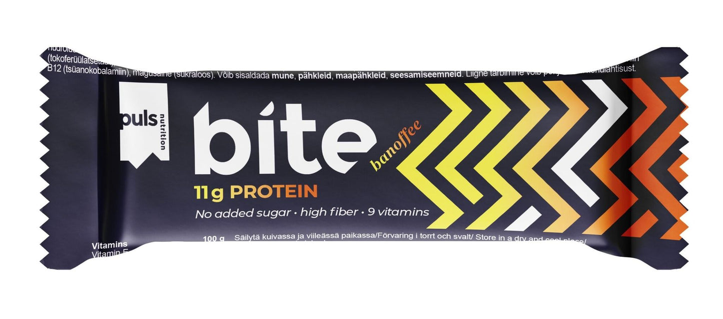 A wrapped protein bar labeled bite banoffee with 11g protein, no added sugar, high fiber, and 9 vitamins. Packaging is rectangular with matte finish. Design shows yellow, orange, and white chevrons on a dark base. Bold sans-serif text in mixed case is used for the label. Product sits alone on a plain surface; background is dark and unpatterned. No people or hands are visible in the shot.