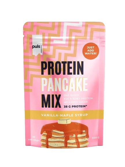A bag of Puls Protein Pancake Mix, vanilla-maple syrup flavor. The package is pink with geometric patterns and shows an illustrated stack of pancakes topped with syrup. The surface has a matte finish. Sans-serif bold fonts in white and gold are used for key product information, including âJust add water!â and â38g protein.â No people or hands are present. Neutral background, front product shot.