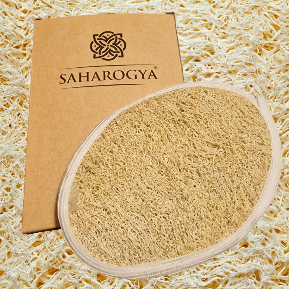 A natural loofah scrubber with a white border lies next to a rectangular brown cardboard box featuring “Saharogya” printed in clear, modern font. Both items rest on an evenly lit, textured loofah mat. No people or additional objects are present in this overhead product shot. A natural loofah scrubber with a white border lies next to a brown Saharogya-branded box, all set on a textured loofah background for an eco-friendly touch.
