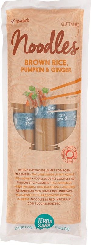 Package of TerraSana gluten-free noodles made with brown rice, pumpkin, and ginger. Clear plastic bag, rectangular shape, glossy finish. Orange and white sans-serif text on front; colorful illustrations of vegetables around the label. Product name and main ingredients visible. Plain background; no people or hands in frame.