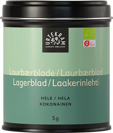 A black tin labeled Urtekram Always Organic contains whole bay leaves, featuring a green and beige design. The surface of the tin is matte. It is rectangular with rounded edges and a fitted lid. Sans-serif bold white text lists product details, including multiple languages and net weight of 5 grams, on the front label. The background is plain white with no people or hands visible in the shot.
