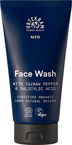 A blue, matte-finish plastic squeeze tube labeled “Urtekram Nordic Beauty Men Face Wash.” The front label in white, modern sans-serif font includes product name and mentions Tazman pepper and salicylic acid. Certifications and ingredient claims are highlighted. No people or hands. The background is plain white with even lighting in a frontal product shot.