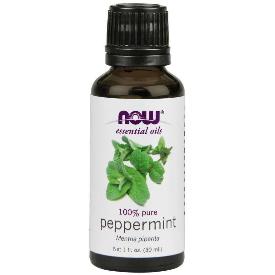 A brown bottle with a smooth, glossy finish, cylindrical in shape and capped with a black screw-on lid. The white front label displays purple and green text in clear printed fonts, along with an image of fresh green peppermint leaves. A brown bottle labeled NOW essential oils 100% pure peppermint, Mentha piperita, 1 fl. oz. (30 mL), featuring an image of fresh peppermint leaves on the front. The product is photographed against a plain white background; no people or hands are visible in the shot.