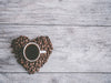 Kahvikuppi sydämeksi muotoiltujen kahvipapujen päällä 