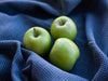 Kolme vihreää omenaa sinisellä pyyheliinalla