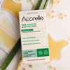 Acorelle Karvanpoistoliuskat Kainaloille ja Bikinialueelle: 20 kappaleen kylmävahaliuskapakkaus kainaloille ja bikinialueelle asetettuna valkoiselle pinnalle yhdessä aloe vera -lehtien, vehnänkorsien ja hunajamaisen vahavalumman kanssa; suorakulmainen mattavalkoinen rasia, vihreää groteskitekstiä, luomusertifikaatin merkki sekä ohut viivapiirros naisesta; ei ihmisiä tai käsiä varsinaisesti kuvassa.