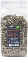 A clear plastic bag of Aduki dried raspberry leaves, labeled in Finnish and Swedish, with visible chopped green and brown leaves inside. The packaging is rectangular with a heat-sealed top edge. Matte paper label shows organic certification stamp, block sans-serif text, and a printed barcode. No people or hands present. Photo uses a neutral background and overhead lighting.