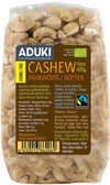 A clear, flexible plastic pouch contains Aduki brand organic Fairtrade cashew nuts, 400g. Cashews are light beige and distinctly visible. The front displays product information and Fairtrade certifications in Finnish and Swedish, with a matte label printed in sans-serif type. The package has a standard rectangular shape. Product photographed against a plain background.