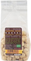 A clear plastic bag of Aduki organic roasted hazelnuts, rectangular in shape, with a matte finish label showing Finnish and Swedish text, nutritional information table, barcode, and 100g net weight. The label uses sans-serif font in black on a white background. No people or hands visible. Neutral, plain background in a close-up product shot.