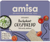 Box of Amisa Organic Buckwheat Crispbread, labeled gluten, wheat, and yeast free, with images of crispbread and tomatoes next to a dip on a light purple background. Features organic ingredients. Net weight 120g. The box has a matte finish with bold sans-serif and serif typography in white and green; no people or hands visible; standard product photo on plain surface.
