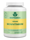 Bioteekki Vegan Monivitamiini, valkoinen muovipullo sylinterimäinen kierrekorkilla ja mattapinnalla; etiketissä vihreitä ja keltaisia korostuksia; typografia moderni groteski, pääteksti "Bioteekki Vegan Monivitamiini", muu tieto sisältää "90 tablets"; ei ihmisiä eikä käsiä näkyvissä, tausta yksinkertainen studiokuva; pullo sisältää 90 tablettia vegaanisia monivitamiineja kasvipohjaisen elämäntavan tueksi.