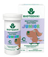 A box and bottle of Bioteekki Junior lactic acid bacteria tablets with vitamin C, featuring a cartoon dog on the Finnish-language packaging. The box contains 60 tablets. Both packages are mostly white with orange and green accents, glossy finish, rectangular box and cylindrical bottle shape. Bold sans-serif text in orange and green. The background is plain white, product centered, no people or hands visible. Shot is a straightforward product photo showing front labels clearly.