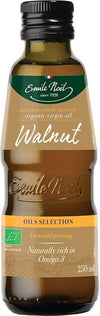 A bottle of Emile Noel organic virgin walnut oil, labeled as first cold pressing and naturally rich in Omega 3, with a green and gold label. The 250 ml bottle highlights its organic quality. Glass bottle with a dark finish, cylindrical shape, glossy surface, plastic screw cap. Printed main text in white and gold serif font on matte-finish label. Neutral background; product centered; no people or other objects visible.