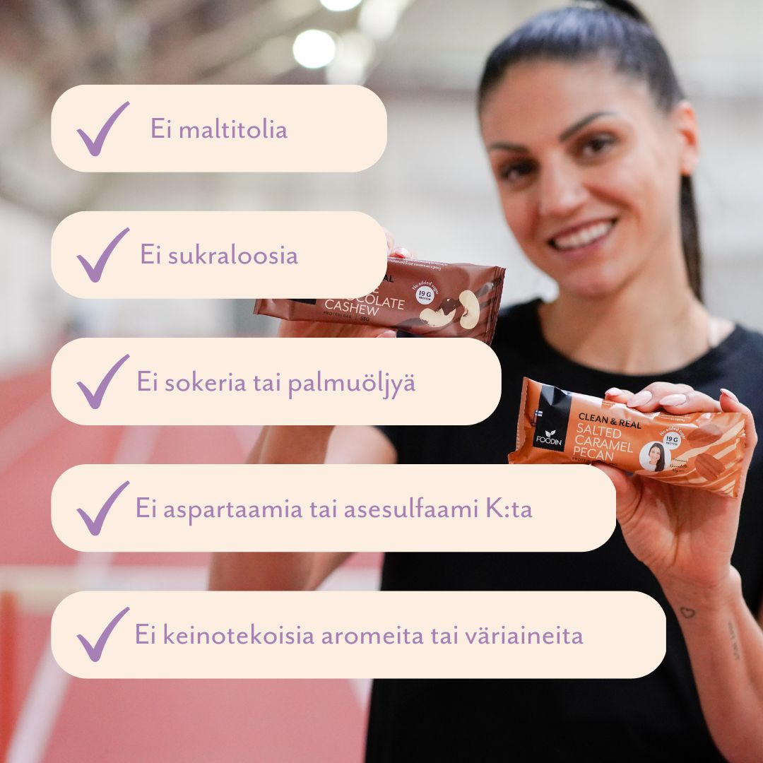 A smiling woman holds two snack bars. The bars are in matte, rectangular wrappers with clear printed labels. Overlay text in Finnish lists absence of certain sweeteners, sugars, palm oil, artificial flavors and colors. Sans-serif typeface is used for the overlay. The scene is set in an indoor sports hall.