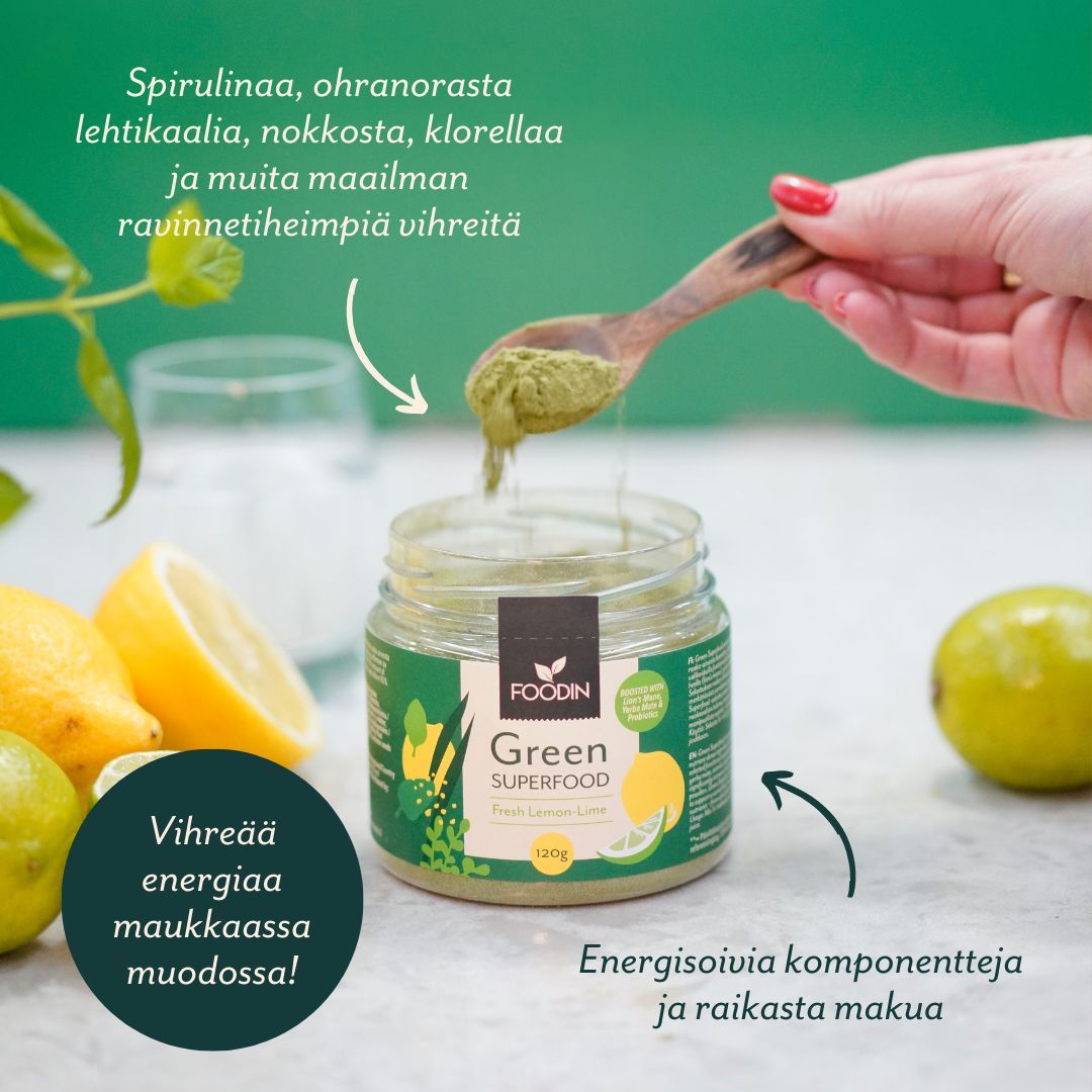 Foodin Green Superfood Fresh Lemon-Lime; käsi kauhaisee vihreää jauhetta purkista, lieriön muotoinen ja musta kierrekorkki, mattapintainen etiketti; ympärillä sitruunoita, lehtivihanneksia ja metallilusikka vaalealla tasaisella alustalla; etiketissä suomenkielinen groteskiteksti; käsi näkyvissä kuvassa.