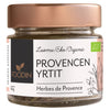 A glass jar with a rose gold metallic screw-top lid labeled FOODIN PROVENCEN YRTIT and Herbes de Provence features a Luomu/Eko/Organic label and charming herb illustrations. The transparent cylindrical jar contains a dried herb mix. The paper label is matte with sans-serif type, additional small text, and stylized botanical drawings. Plain white background, no people visible.