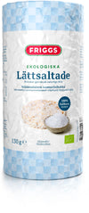 A package of Friggs organic lightly salted rice cakes, labeled as gluten-free and made from wholegrain brown rice. The packaging is cylindrical with a matte white finish and blue checkered side panels. There is a photographic image of a single rice cake on the front. Sans-serif font is used for visible text. Product sits against a plain background in an upright position.
