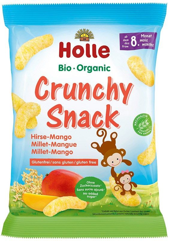 Bag of Holle Bio Organic Crunchy Snack, millet-mango flavor, for babies 8 months and older. The packaging is matte plastic in light yellow-orange tones with a gusseted base, upright rectangular shape. Illustrated puffs, mango slices, millet grains, and two cartoon monkeys are printed on the front. Product name appears in simple sans-serif font; text is multilingual. Plain studio background, no people present.