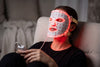 Innolux RED MASK -punavalomaski käytössä, punainen valo palaa, ohjain kädessä