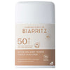 Laboratoires de Biarritz Tinted Sunscreen Stick SPF50+ (Sävytetty Aurinkovoidepuikko): valkoinen ja beige sylinterimäinen puikko mattapinnalla, lihavoitu groteskiteksti; etiketissä maininnat epäpuhtauksien ja arpien peittämisestä, luomusertifikaattien logot sekä sävytetty suoja; muovinen pakkaus, tuotetiedot painettu suoraan etikettiin; tausta on valkoinen, tuote keskellä kuvaa, ei ihmisiä tai käsiä näkyvissä.