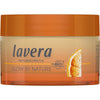 Lavera Glow By Nature Vitamin C 3in1 Cream; pyöreä oranssi muovipurkki yhteensopivalla kannella, kiiltävä pinta ja kompakti muoto; etiketissä lukee ”Lavera Naturkosmetik Glow by Nature”, osittainen kuva appelsiiniviipaleesta ja teksti ”Mit Bio” sekä vitamiinitietoja selkeällä groteskikirjasimella; vaalea tausta, ei ihmisiä tai esineitä; tavanomainen tuotekuva.