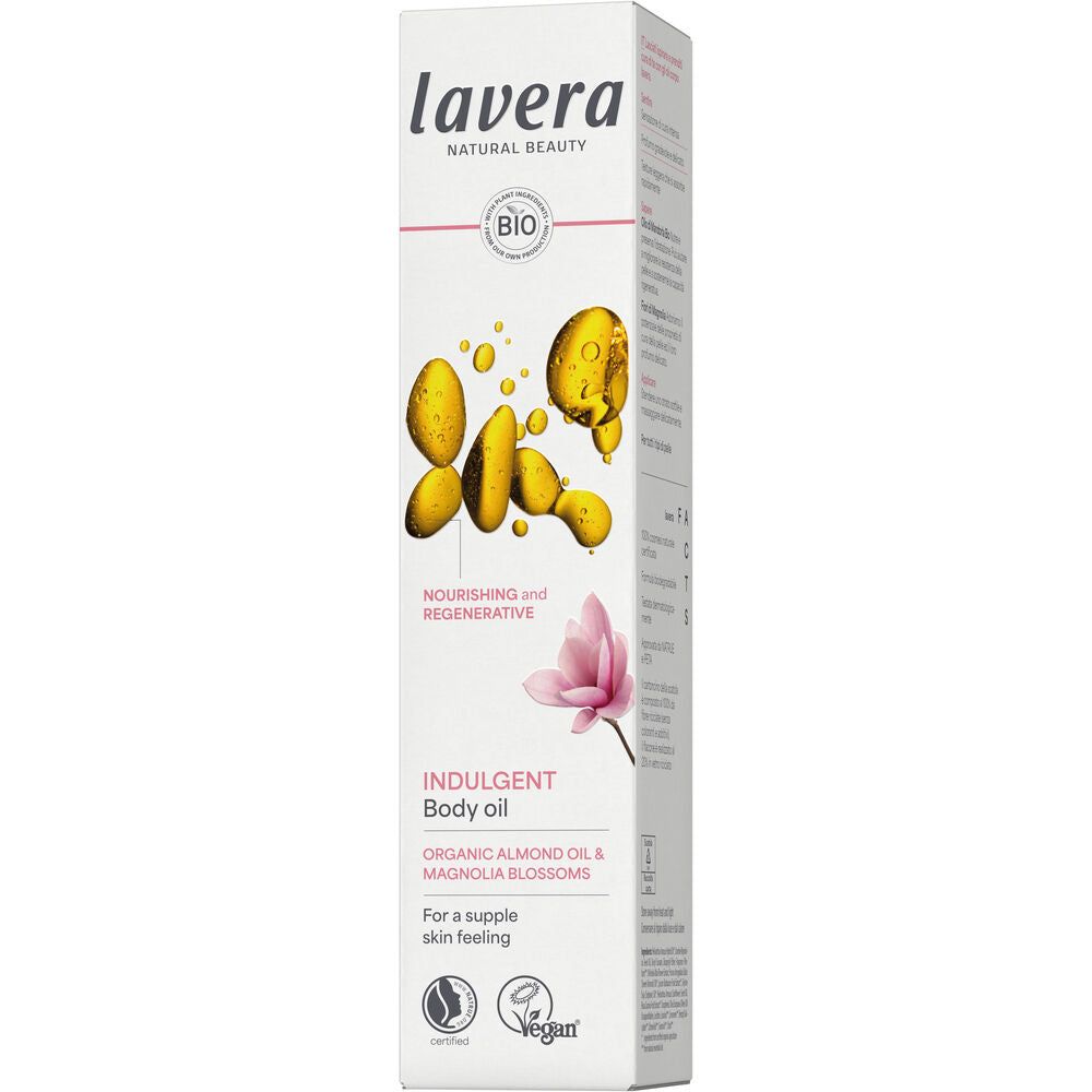 Lavera Indulgent Vartaloöljy; rasia Lavera Indulgent Body Oil -tuotetta luomumanteliöljyllä ja magnolian kukilla; pakkauksessa keltaisia öljypisaroita ja vaaleanpunainen kukka sekä vegaani-, eläinkokeeton- ja luomusertifiointimerkkejä; rasia suorakaiteen muotoinen mattapinnalla, pääosin valkoinen keltaisin ja vaaleanpunaisin elementein; tikkukirjasinta näkyvässä tuotenimessä ja ainesosatekstissä; ei ihmisiä tai käsiä kuvassa; tausta tasainen valkoinen studiotuotekuvatyylisesti.