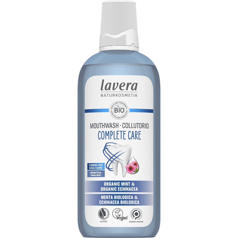 A bottle of Lavera Complete Care Mouthwash with organic mint and echinacea. Cylindrical clear plastic bottle shows blue liquid inside, white screw cap on top. White label features blue accents, sans-serif text, and small round icons for vegan and cruelty-free. Main label text is centered. The background is plain white, no people or props visible. Shot is straight-on front view of the product.