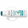 A white bottle of Lavera Volume & Strength Shampoo with mint on the label lies on a white surface. The cap is teal and open. Glossy plastic packaging, cylindrical with a rounded shoulder and flat base. Surrounded by visible pools of shampoo and foam swirls. Sans-serif text in black and teal reads “Volume & Strength Shampoo.” No people or hands are present in the shot.