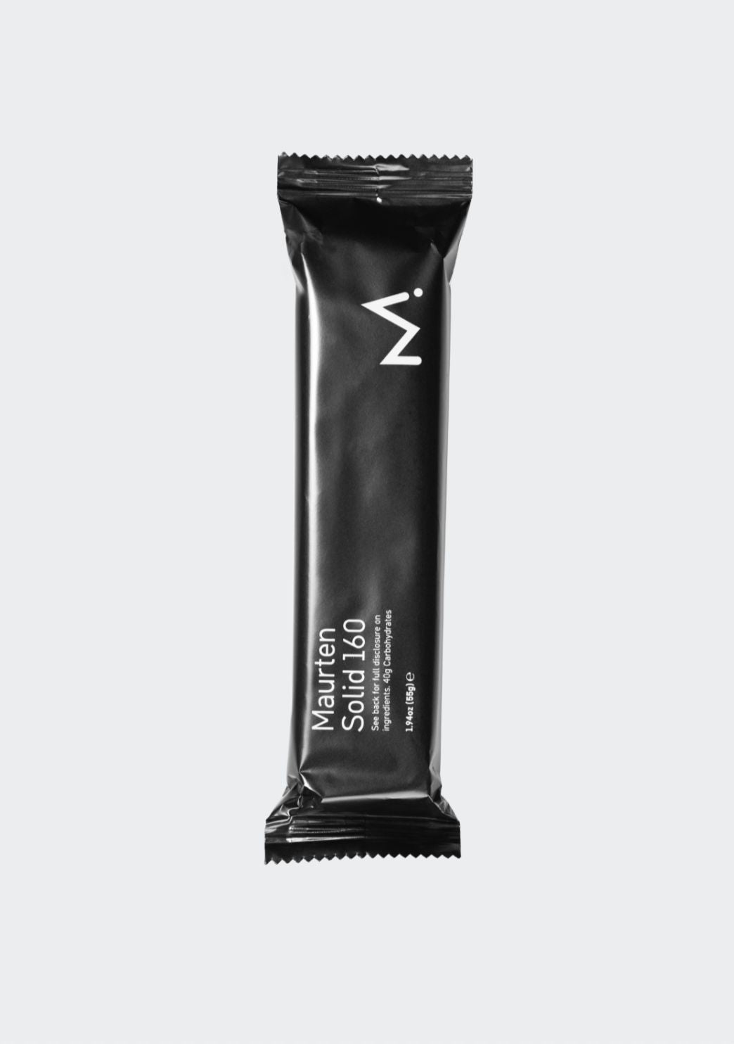 A black energy bar wrapper labeled Maurten Solid 160 features minimalistic white text and a bold white M logo at the top. The packaging is rectangular with a matte finish, no visible texture, and straight sealed edges. Typography is sans-serif in different weights. The background is plain light gray, with no props or people. Shot shows only the full, unopened product centered in frame.