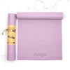 A rolled and unrolled lavender yoga mat with a myoga logo is displayed on a plain white surface. The mats are rectangular with a matte finish and slightly textured surface. The rolled mat is secured by a brown paper label, which shows an illustration of a person in a yoga pose and text in bold sans-serif font. No people or hands are present in the image.