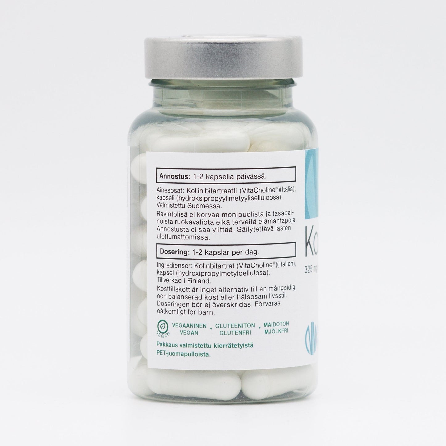 A clear cylindrical plastic bottle of white capsules with a silver screw-on lid. The label is matte and wrapped around the bottle, displaying dosage instructions, ingredients, and icons for vegan, gluten-free, and lactose-free. Text appears in Finnish and Swedish using simple sans-serif fonts. The image background is plain white with no visible people or actions.
