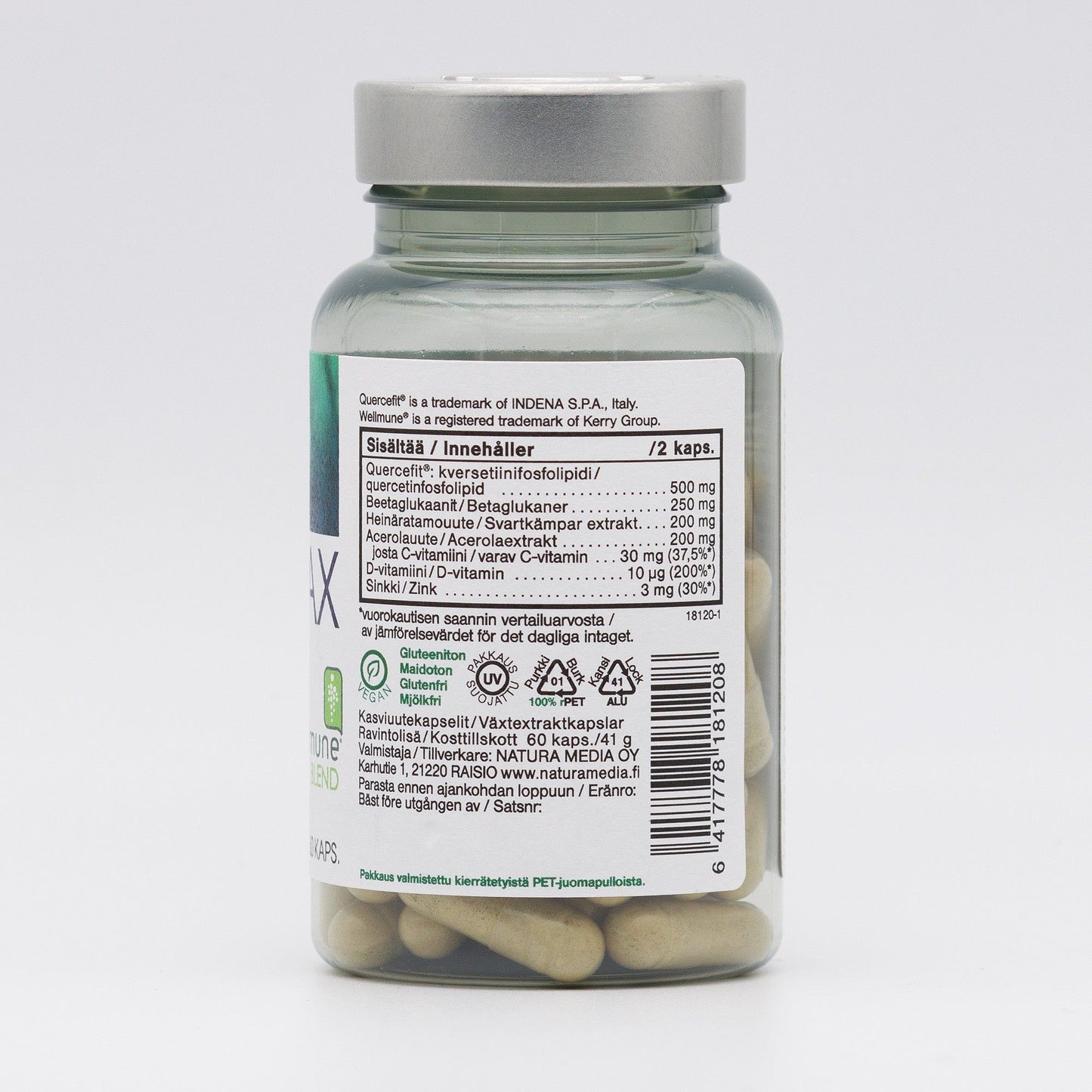 A clear bottle with a grey cap contains beige capsules. The bottle is cylindrical and made of plastic with a smooth, glossy surface. A white rectangular label wraps around the bottle, featuring printed ingredients and nutritional information in Finnish and Swedish. Label text uses standard sans-serif fonts in black. Plain background; no people or hands present. Shot is straight-on.