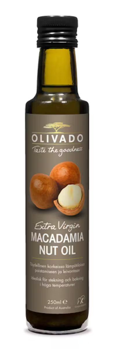 A bottle of Olivado Extra Virgin Macadamia Nut Oil with a brown, glossy label and images of whole and cracked macadamia nuts. The bottle is cylindrical, dark glass, 250ml size. Legible text on the label includes product name and origin details. Background is plain and neutral. No people or hands are visible in the image.