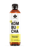 A bottle of Puhdistamo kombucha with ginger and lemon flavor, featuring a yellow label, black cap, and Finnish text. The bottle contains a light amber kombucha. The bottle is cylindrical and made of clear glass with a matte finish label. Typography on the label is bold sans-serif in black and white. The product stands upright on a plain white background; no people or additional objects are visible.