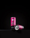 Two pink cans of energy drink rest on a black surface, one upright and one lying down. They are standard aluminum cans with a glossy finish and covered in condensation. The design features bold, modern typography displaying “raspberry flavor” and “180 mg caffeine” on the label. No people or hands present. The shot is against a solid black background.