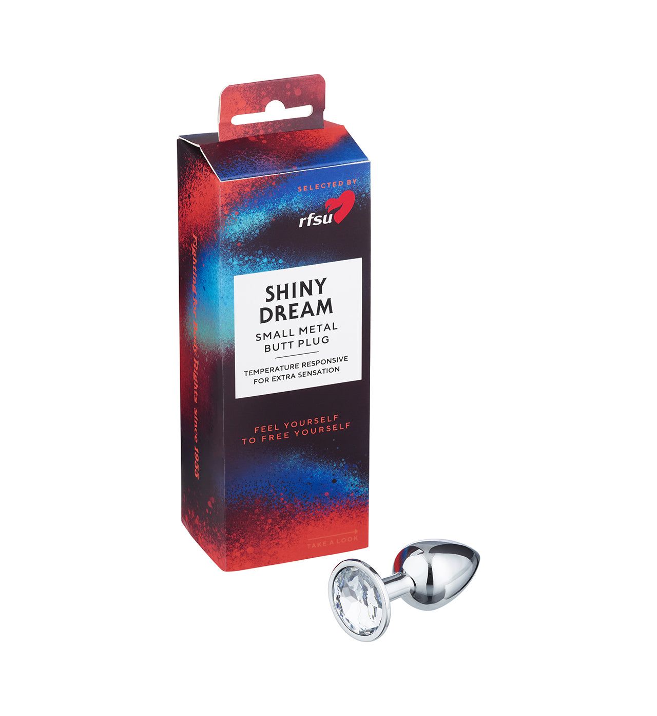 A small, shiny metal butt plug with a gem-like base rests next to its colorful packaging labeled SHINY DREAM Small Metal Butt Plug by RFSU. The product is silver with a reflective finish and has a smooth surface, teardrop shape, and clear faceted gem at the base. Packaging features red and blue graphic accents and prominent label text on the front. Box stands upright on a plain background.