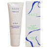 A tube of SEES Forest Kiss lip balm stands next to its box. Both items have a matte finish, with packaging decorated by blue and green abstract lines and simple sans-serif text. The label reads that the balm is infused with forest microbes and peppermint. The shot uses a plain background, no people or hands are present.