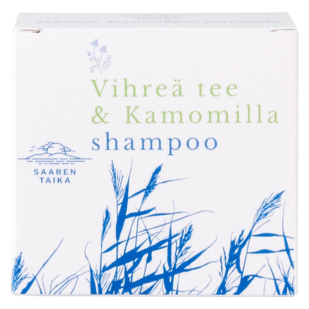 Saaren Taika Palashampoo Vihreä Tee & Kamomilla, valkoinen pakkaus sinisellä ja vihreällä tekstillä "Vihreä tee & Kamomilla"; pakkauksessa sinisiä ruohokuvituksia ja Saaren Taika -logo; pakkaus suorakaiteen muotoinen ja mattapintainen, tuotenimi lihavoidulla monivärisellä groteskifontilla; kuvattu suoraan edestä vaaleaa taustaa vasten, ei ihmisiä eikä käsiä näkyvissä.