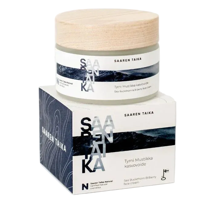 Saaren Taika Tyrni Mustikka Kasvovoide; purkki puukantisena rasian päällä, molemmat tekstillä Saaren Taika Skincare; molemmat suorakulmaisia siistein reunoin, purkki sylinterin muotoinen ja rasia kuutiomainen; pakkaus valkoinen tummansinisin korostuksin ja tyylitellyllä luontoaiheella; etiketin kirjasin serifi tummansinisenä; tausta tasainen, ei ihmisiä tai käsiä kuvassa.