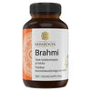 A brown plastic bottle with a screw cap, cylindrical in shape. The matte label has gold elements on white and orange areas. Typography uses clear, sans-serif fonts for legible product and ingredient information. No visible people or hands. Neutral studio background, straight-on product shot. A brown bottle labeled Saharogya Brahmi features text in Finnish and Swedish, highlighting its support for focus and memory. The label indicates 60 vegan capsules and showcases a gold design set against a white and