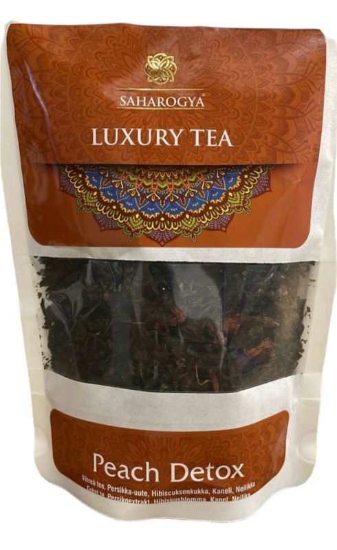 A package of Saharogya Luxury Tea, labeled as Peach Detox, features a multicolored decorative pattern on a matte-finish rectangular pouch. The front has a transparent window showing loose tea leaves. Typography is bold and clear. No people or hands are present. Plain background with direct product lighting.