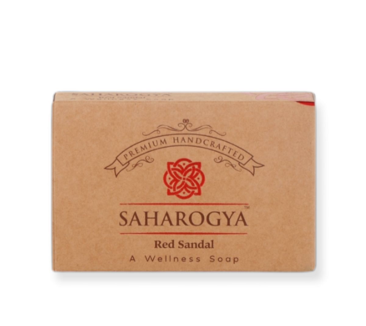 A rectangular brown box labeled “SAHAROGYA Red Sandal A Wellness Soap” is visible. The packaging is matte, features a decorative red design, and includes the words “Premium Handcrafted” above the main logo in serif font. No people or hands are present, and the background is plain. Shot type is front-facing product-only. A rectangular brown box labeled SAHAROGYA Red Sandal A Wellness Soap features a decorative red design and the text Premium Handcrafted above the logo, highlighting its natural wellness